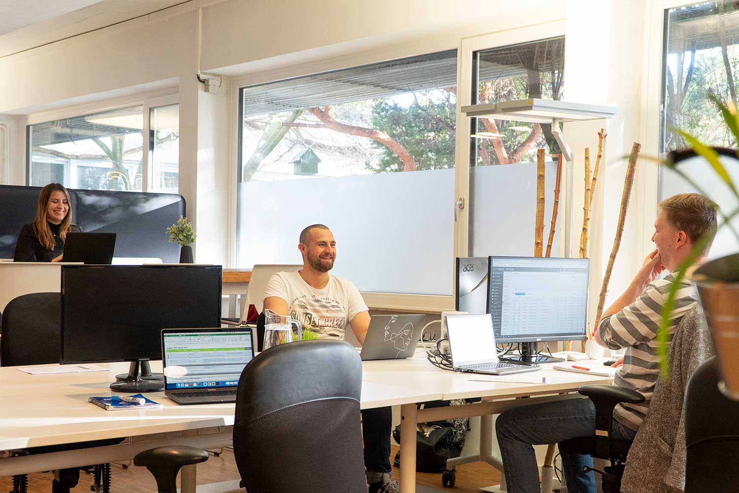 Drei Menschen am arbeiten und lachen im PINC Coworking Space.